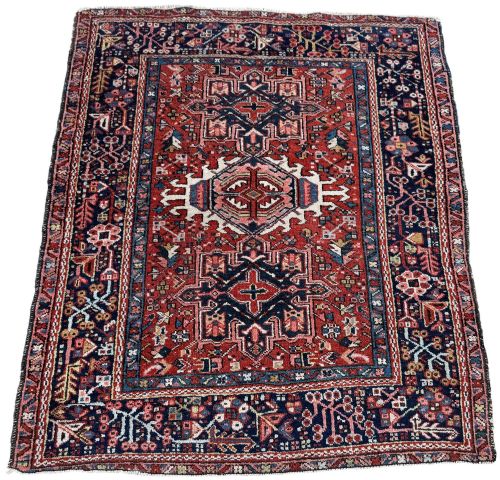 fig 1. An antique hand-knotted Karaja rug featuring three geometric central medallions in pink, blue, and navy on a crimson red field surrounded by a dark navy border.