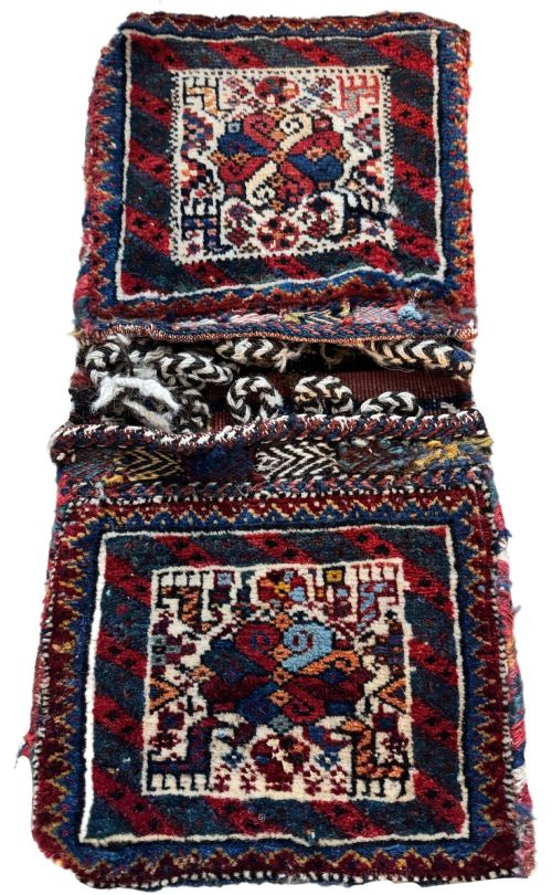 fig 1. An antique handwoven Qashqai wool Khorjin double saddlebag featuring geometric medallions in red, navy, and cream with braided closure loops.