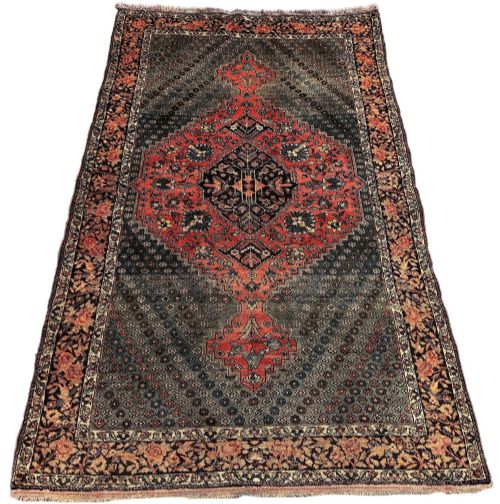 fig 1. An antique hand-knotted Bakhtiar wool rug featuring a central terracotta stepped medallion on a dark indigo field filled with intricate floral motifs.