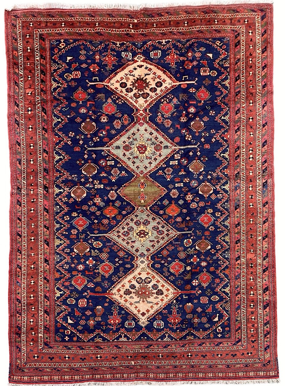 A vintage Persian Afshar wool rug measuring 2.92m by 2.03m featuring a navy blue field with diamond medallions and a red geometric border.