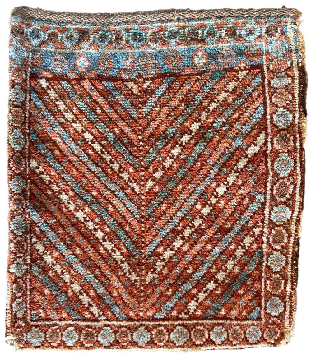 An antique hand-knotted Kurdish chanteh bag face featuring diagonal chevron stripes in terracotta red and teal blue bordered by a geometric motif.