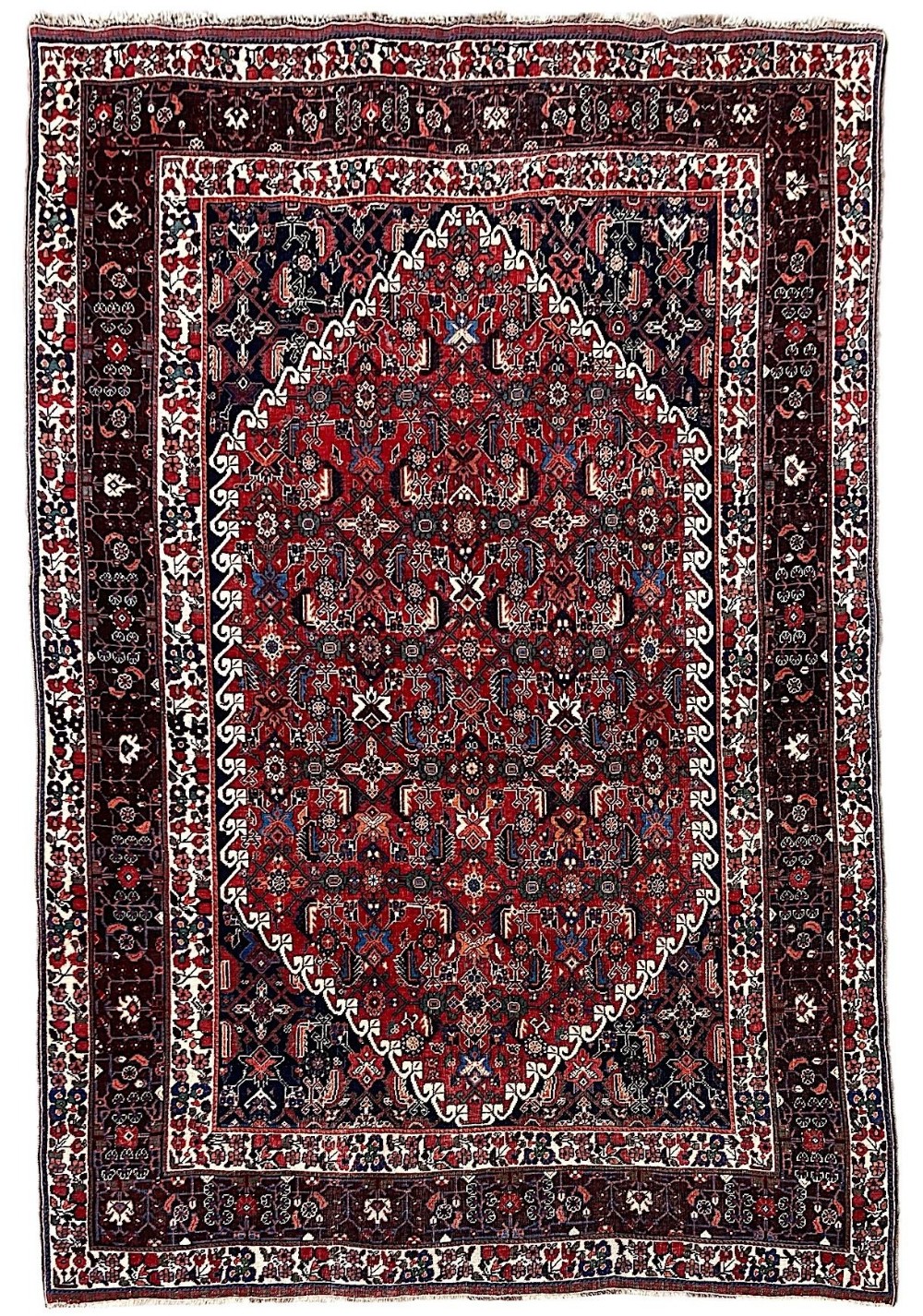 An antique hand-knotted Qashqai rug with a central stepped medallion in red and navy blue surrounded by geometric tribal motifs and patterned borders.