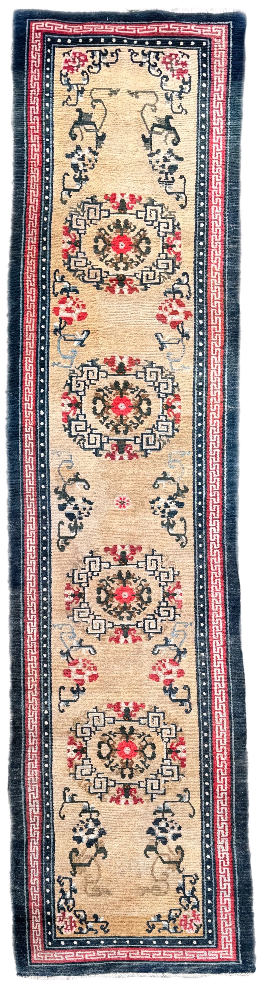 A long antique Tibetan wool runner rug featuring four circular geometric medallions on a beige field bordered by red key-fret patterns and indigo blue edges.