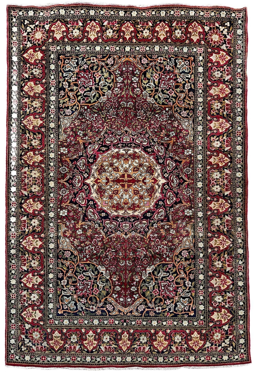 A rectangular hand-knotted Persian Isfahan rug featuring an intricate central medallion surrounded by dense floral scrollwork in shades of crimson red, navy blue, and ivory.