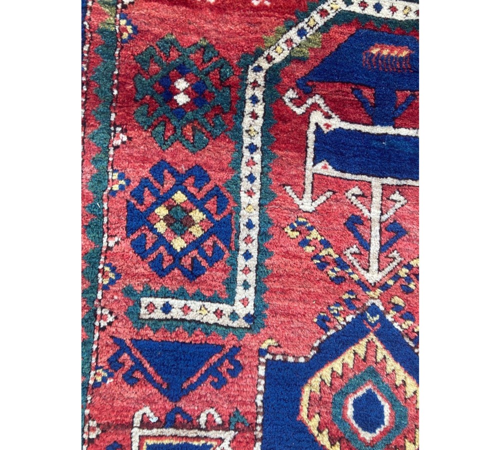 A hand-knotted Caucasian prayer rug featuring a red central field with a pointed mihrab niche, geometric medallions, and multi-band patterned borders in navy blue, red, and cream. View XV