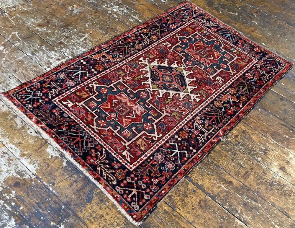 An antique hand-knotted Karaja wool rug featuring three distinct geometric medallions in red, navy blue, and ivory tones surrounded by a dense tribal border. View V