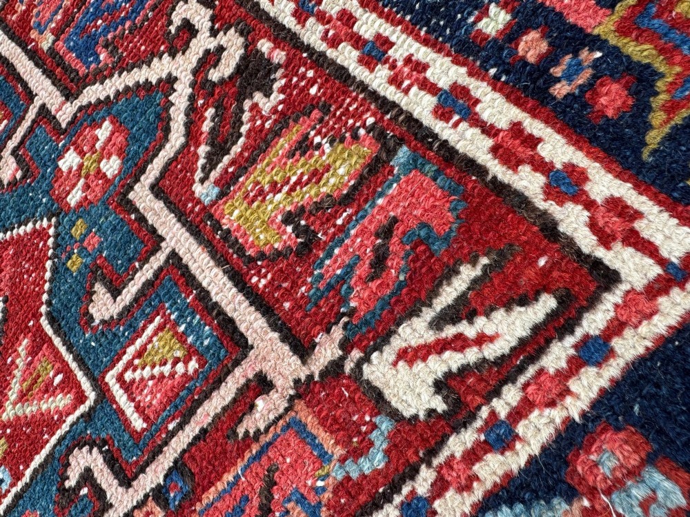 An antique hand-knotted Karaja wool rug featuring three distinct geometric medallions in red, navy blue, and ivory tones surrounded by a dense tribal border. View X