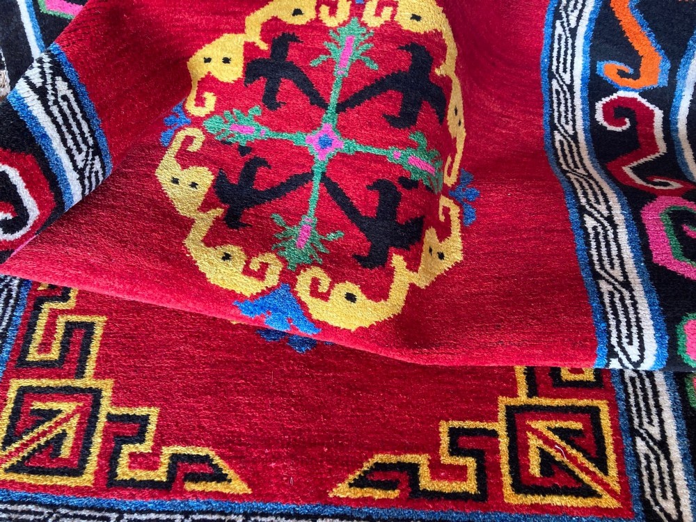 A hand-knotted rectangular Tibetan wool rug featuring a bright red centre field with three yellow and green central medallion motifs framed by a black cloud-scroll border. View XII
