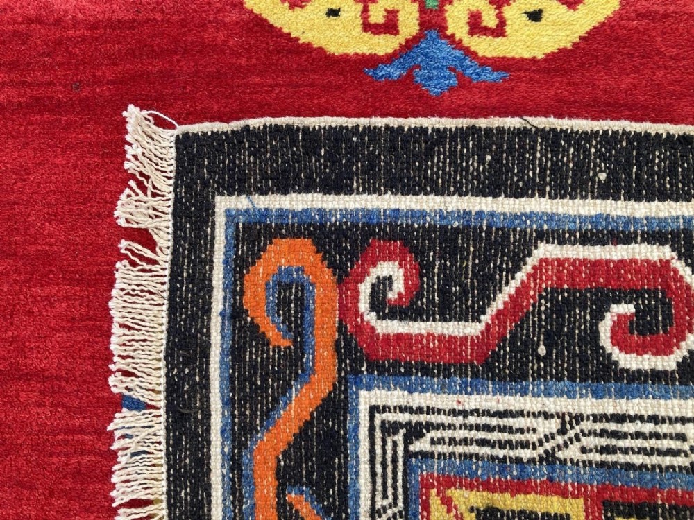A hand-knotted rectangular Tibetan wool rug featuring a bright red centre field with three yellow and green central medallion motifs framed by a black cloud-scroll border. View XIII