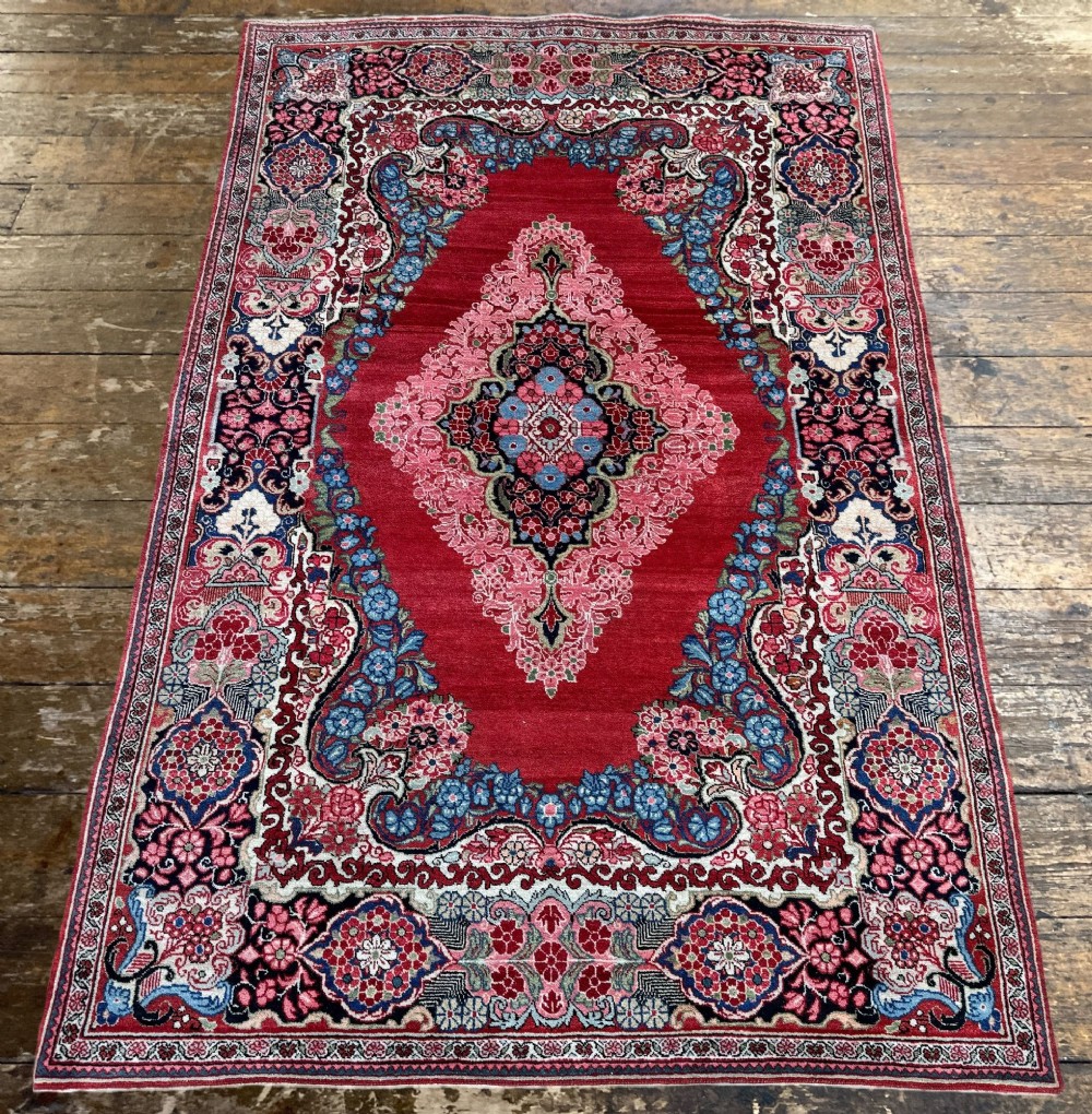 Hand-knotted antique Persian Sarouk wool rug featuring a large central floral medallion on a rich red ground with elaborate decorative borders. View IV