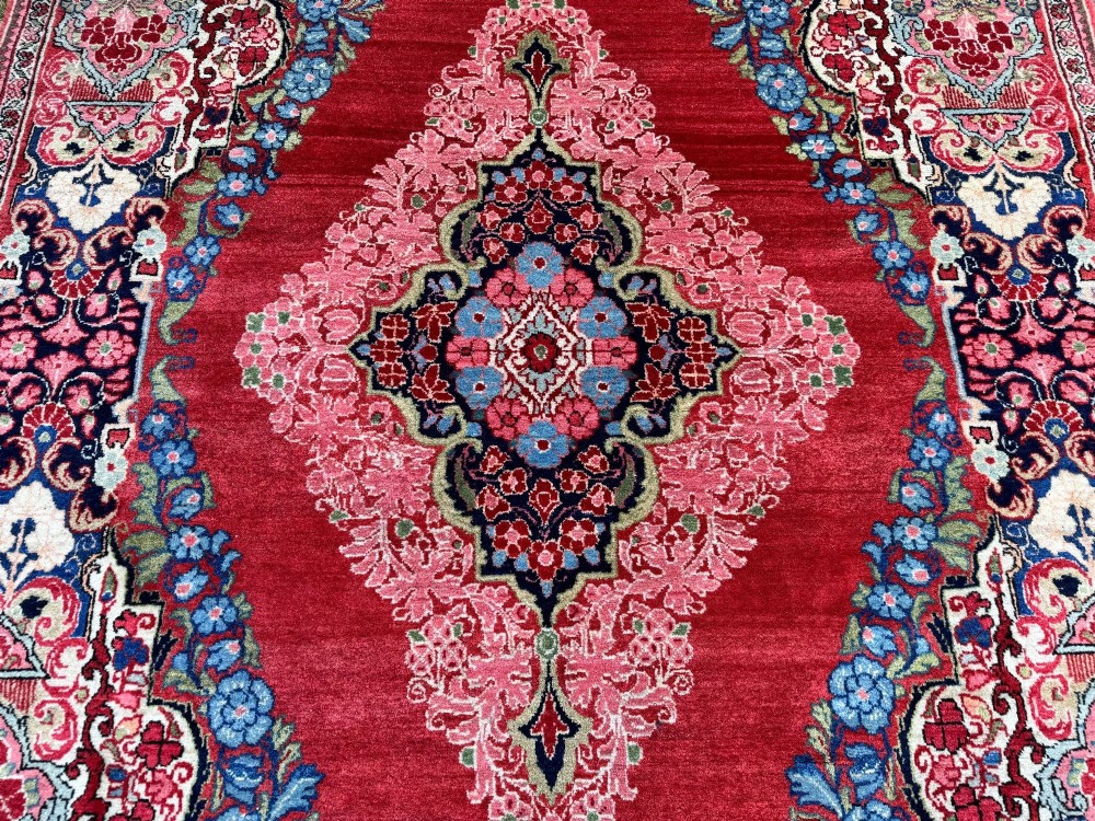 Hand-knotted antique Persian Sarouk wool rug featuring a large central floral medallion on a rich red ground with elaborate decorative borders. View VIII