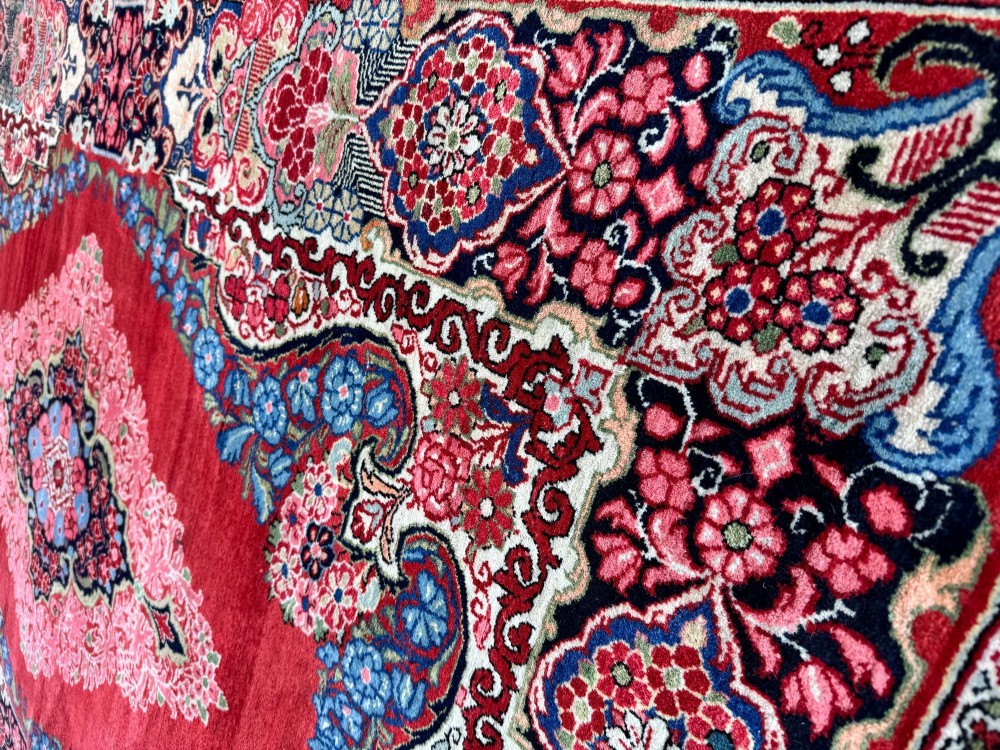 Hand-knotted antique Persian Sarouk wool rug featuring a large central floral medallion on a rich red ground with elaborate decorative borders. View IX