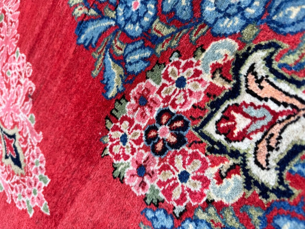 Hand-knotted antique Persian Sarouk wool rug featuring a large central floral medallion on a rich red ground with elaborate decorative borders. View X