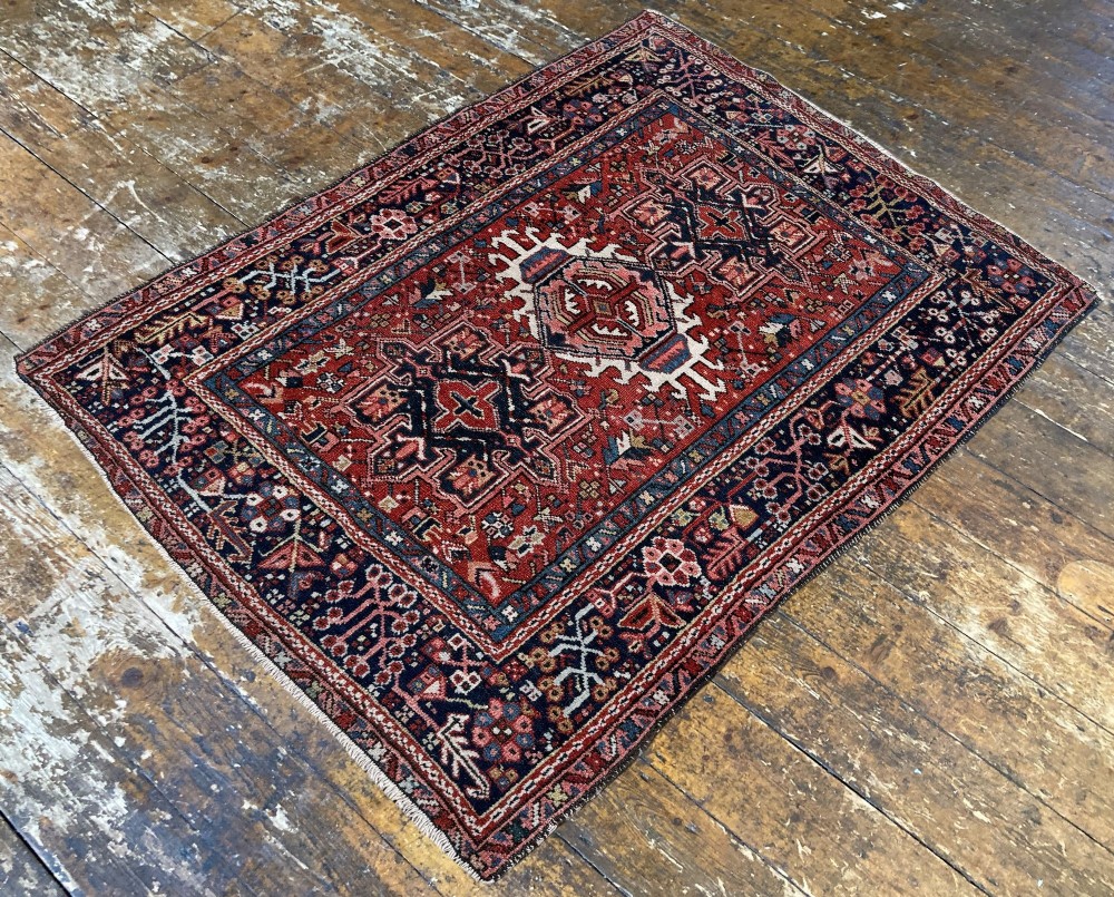 An antique hand-knotted Karaja rug featuring three geometric central medallions in pink, blue, and navy on a crimson red field surrounded by a dark navy border. View V