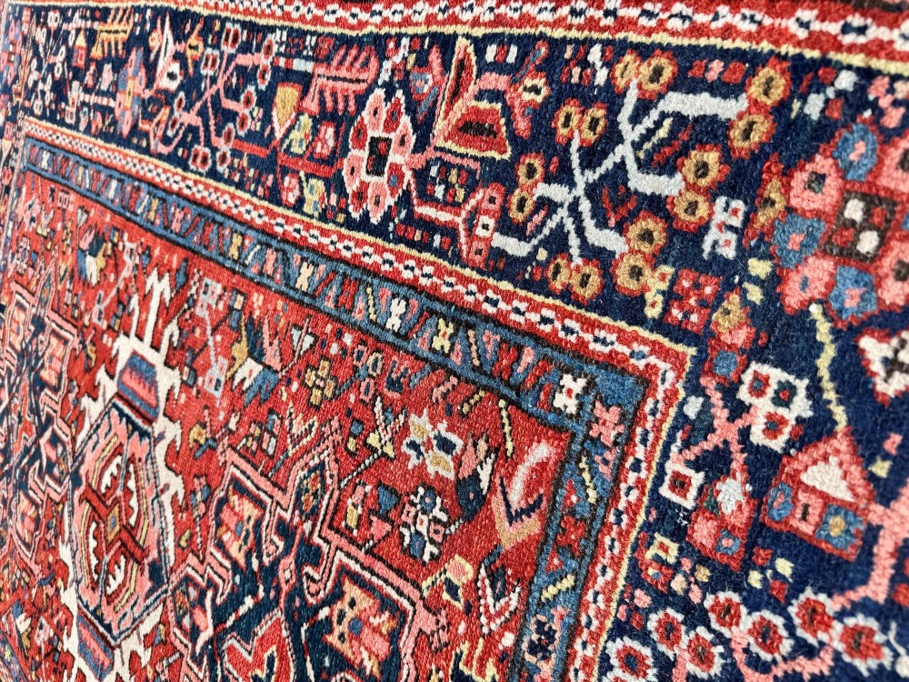An antique hand-knotted Karaja rug featuring three geometric central medallions in pink, blue, and navy on a crimson red field surrounded by a dark navy border. View IX