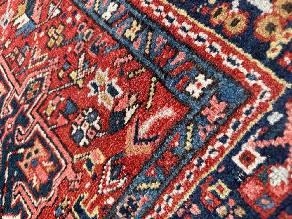 An antique hand-knotted Karaja rug featuring three geometric central medallions in pink, blue, and navy on a crimson red field surrounded by a dark navy border. View X