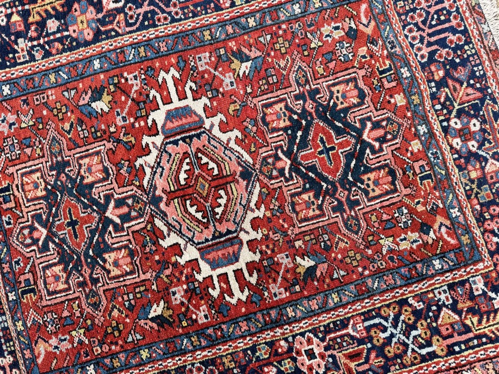 An antique hand-knotted Karaja rug featuring three geometric central medallions in pink, blue, and navy on a crimson red field surrounded by a dark navy border. View XI