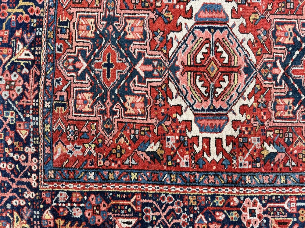 An antique hand-knotted Karaja rug featuring three geometric central medallions in pink, blue, and navy on a crimson red field surrounded by a dark navy border. View XII