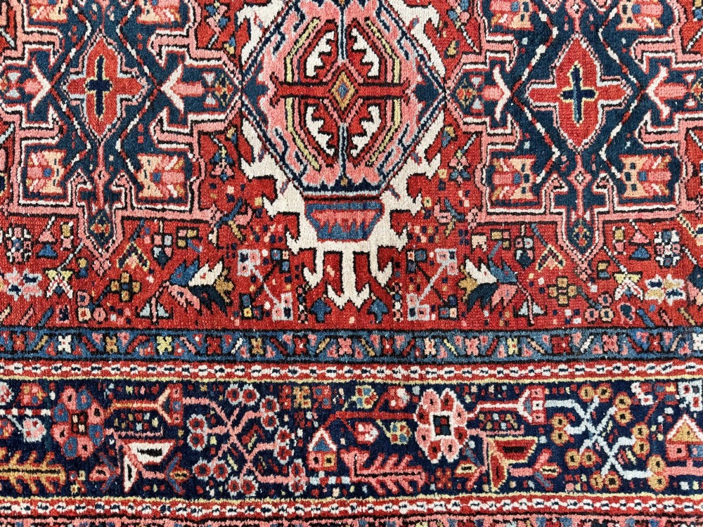 An antique hand-knotted Karaja rug featuring three geometric central medallions in pink, blue, and navy on a crimson red field surrounded by a dark navy border. View XIII