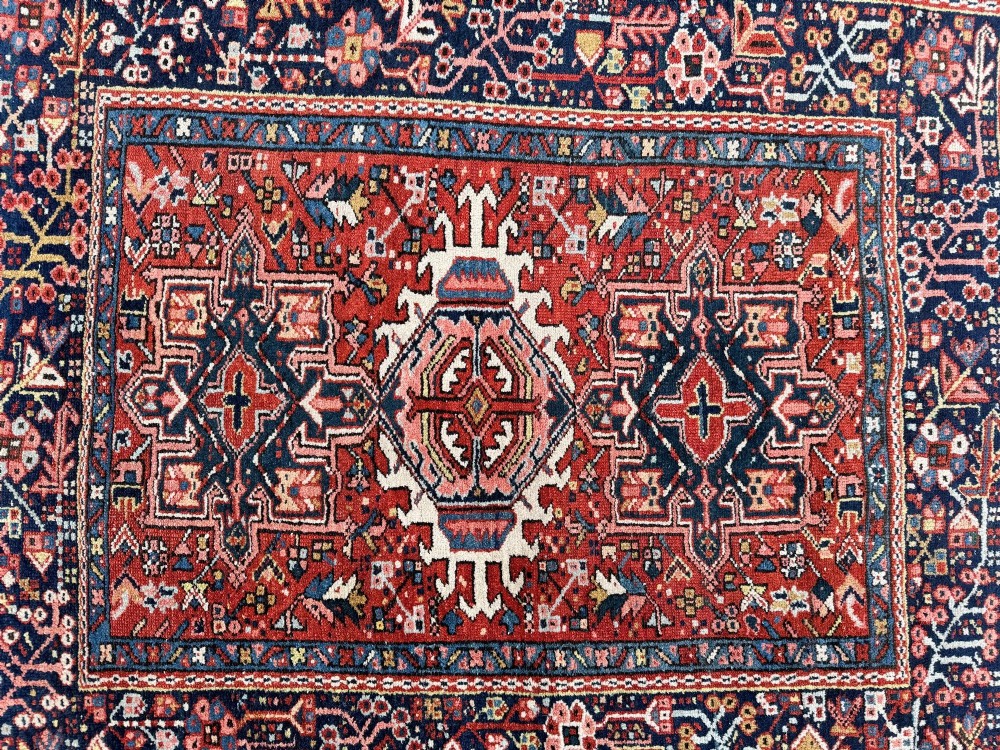 An antique hand-knotted Karaja rug featuring three geometric central medallions in pink, blue, and navy on a crimson red field surrounded by a dark navy border. View XIV