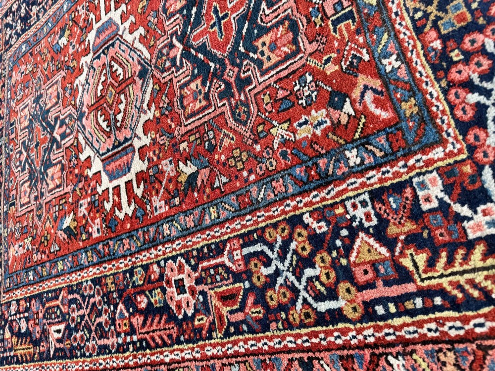 An antique hand-knotted Karaja rug featuring three geometric central medallions in pink, blue, and navy on a crimson red field surrounded by a dark navy border. View XV