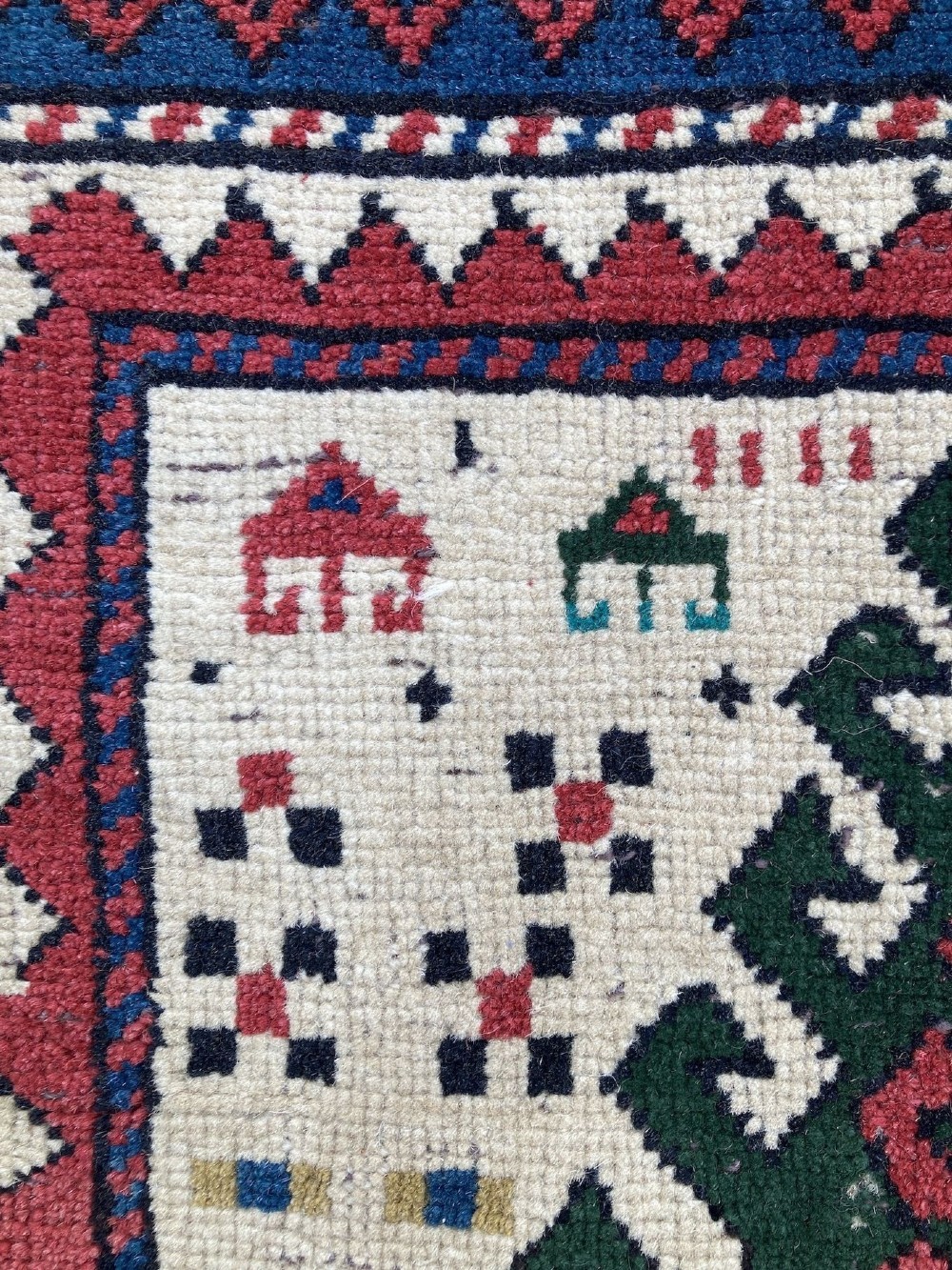 An antique hand-knotted Caucasian Kazak wool rug featuring three stacked geometric medallions on an ivory ground with multi-coloured geometric borders. View XI