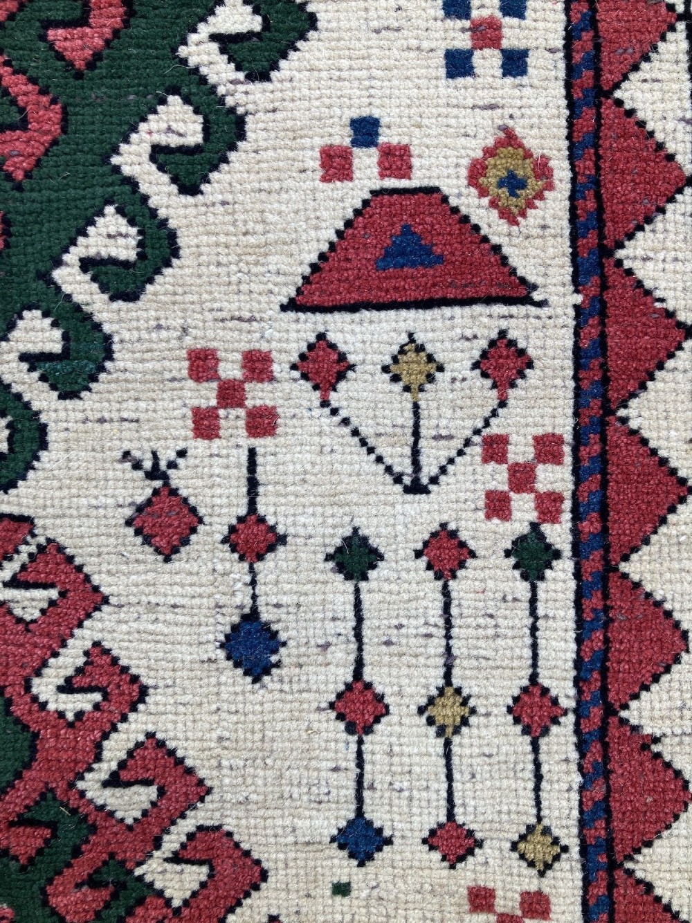 An antique hand-knotted Caucasian Kazak wool rug featuring three stacked geometric medallions on an ivory ground with multi-coloured geometric borders. View XII