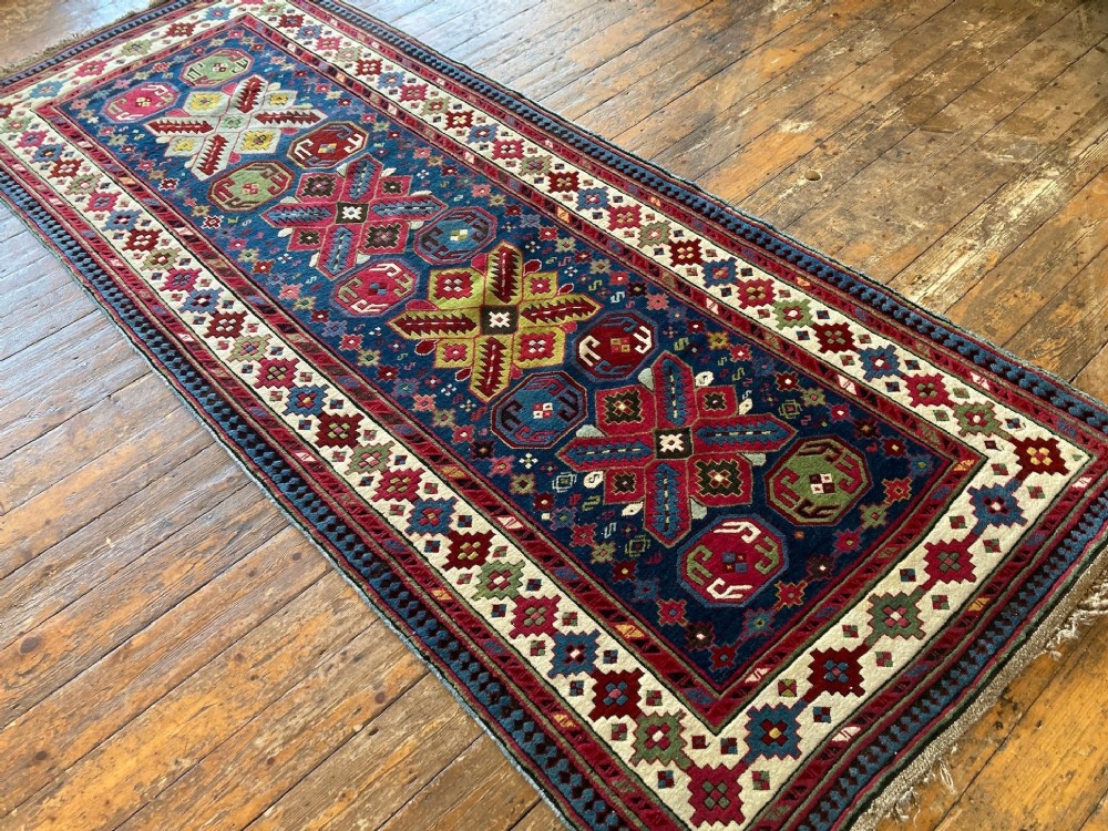 An elongated Caucasian Talish runner rug featuring geometric star motifs and octagons set against a deep indigo field with patterned borders. View IV