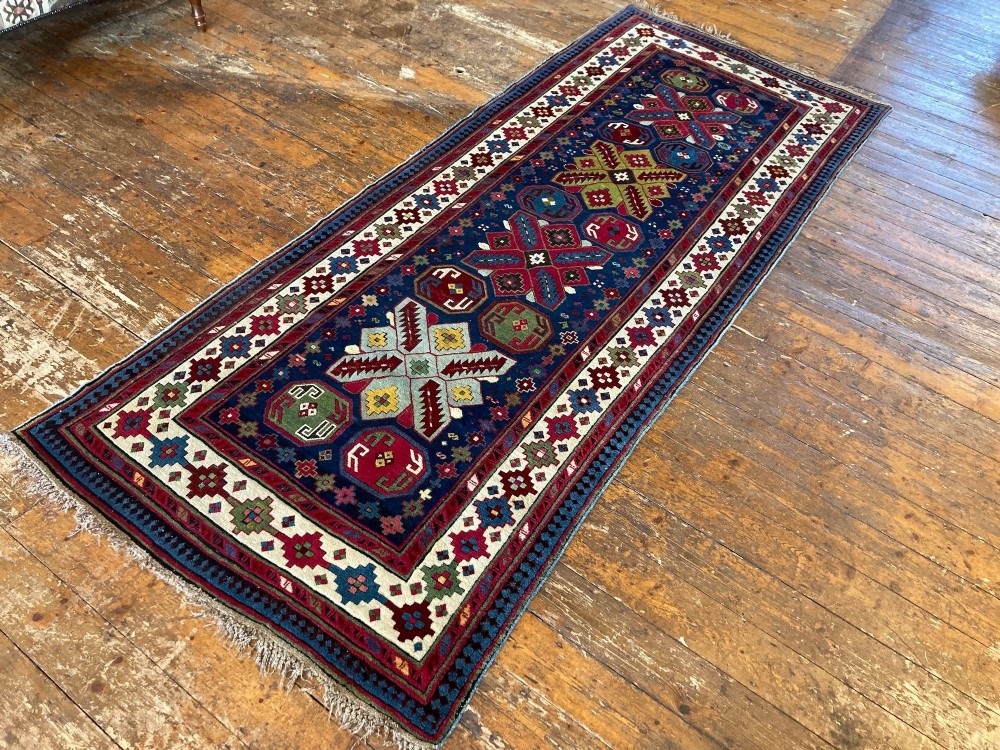 An elongated Caucasian Talish runner rug featuring geometric star motifs and octagons set against a deep indigo field with patterned borders. View V