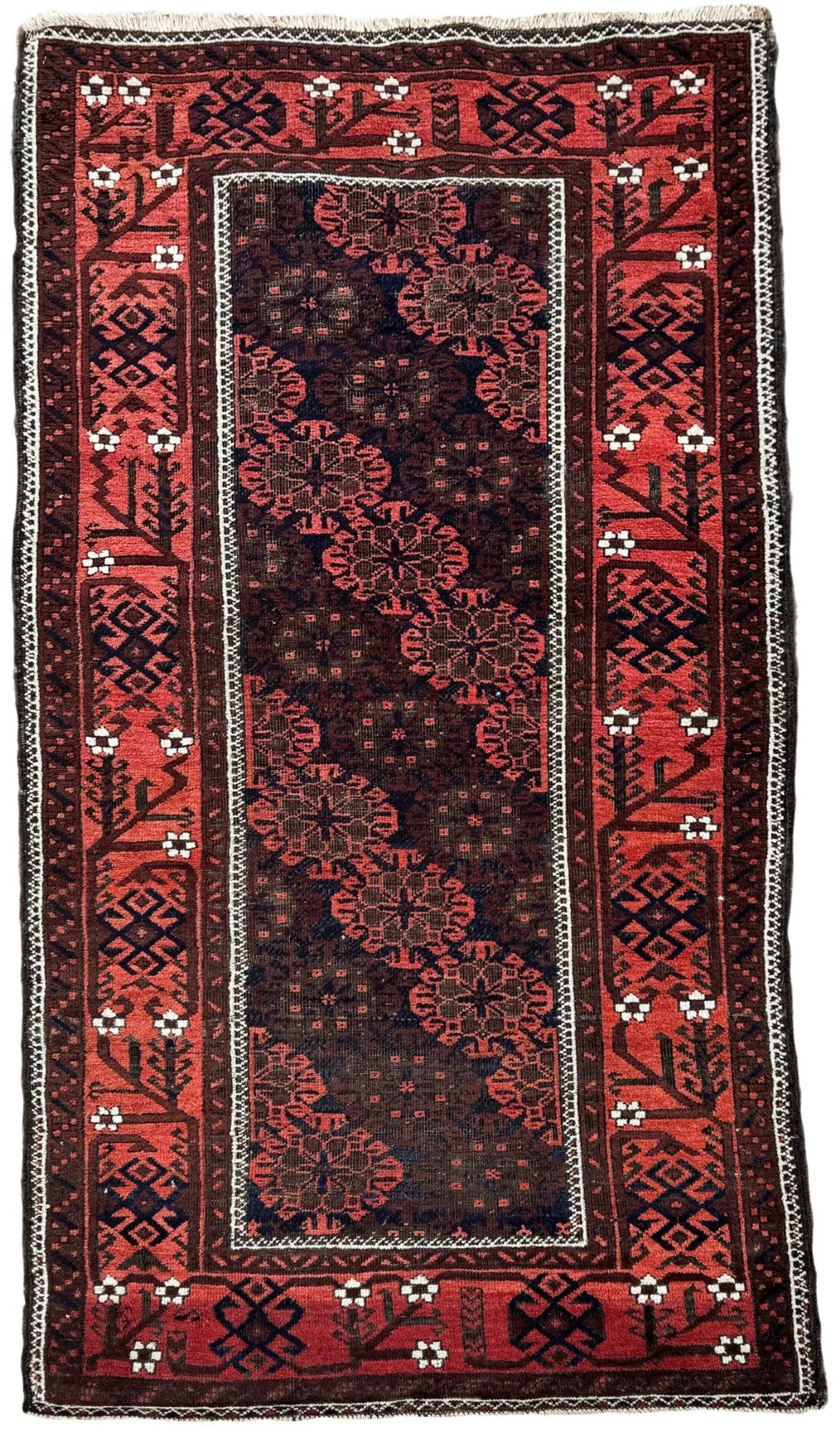An antique hand-knotted Belouch wool rug featuring geometric star motifs, a dark brown central field, and a deep red patterned border.