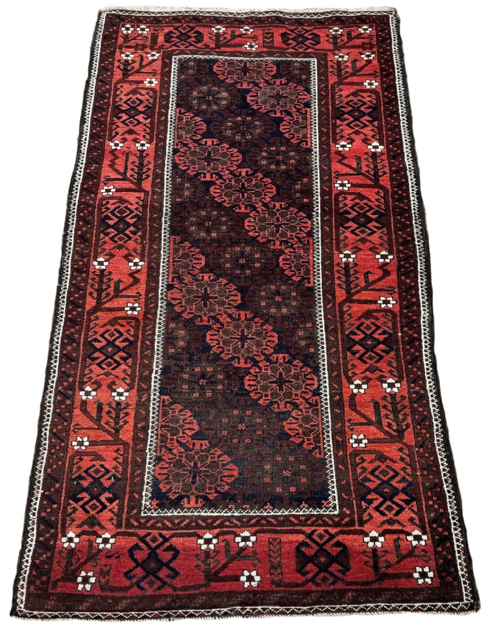 An antique hand-knotted Belouch wool rug featuring geometric star motifs, a dark brown central field, and a deep red patterned border. View II