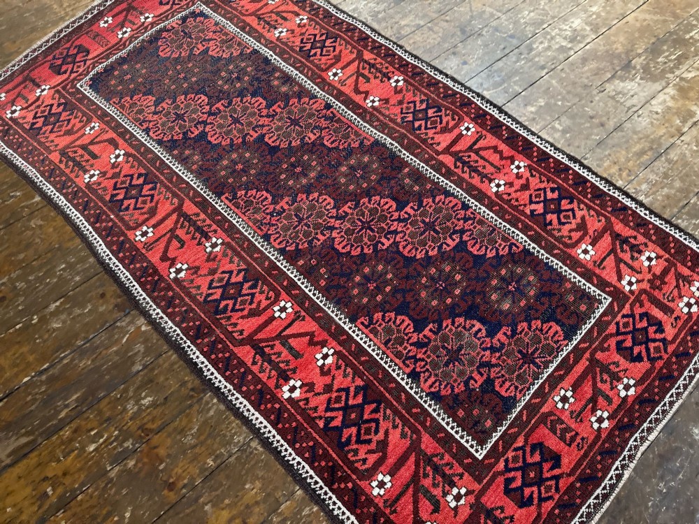 An antique hand-knotted Belouch wool rug featuring geometric star motifs, a dark brown central field, and a deep red patterned border. View VI