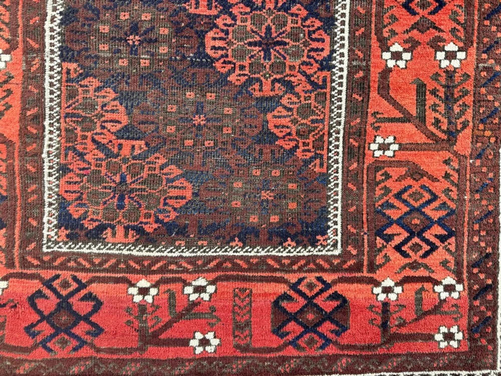 An antique hand-knotted Belouch wool rug featuring geometric star motifs, a dark brown central field, and a deep red patterned border. View VII