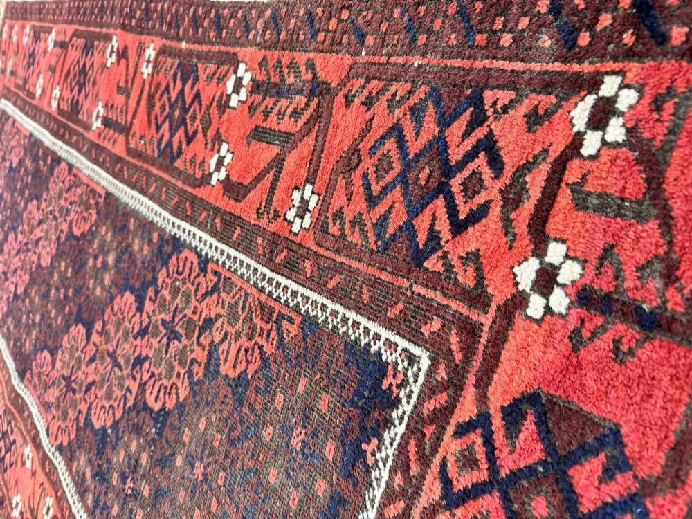 An antique hand-knotted Belouch wool rug featuring geometric star motifs, a dark brown central field, and a deep red patterned border. View IX
