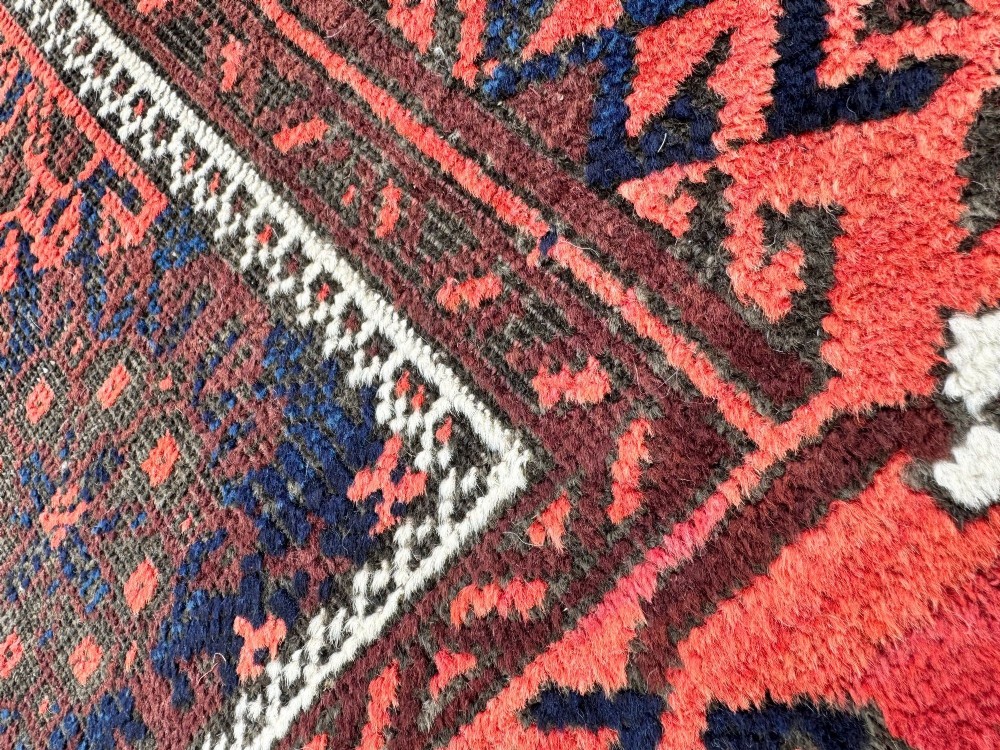 An antique hand-knotted Belouch wool rug featuring geometric star motifs, a dark brown central field, and a deep red patterned border. View X