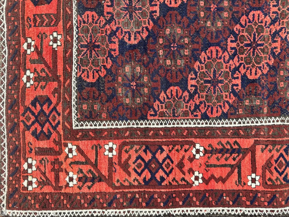 An antique hand-knotted Belouch wool rug featuring geometric star motifs, a dark brown central field, and a deep red patterned border. View XII
