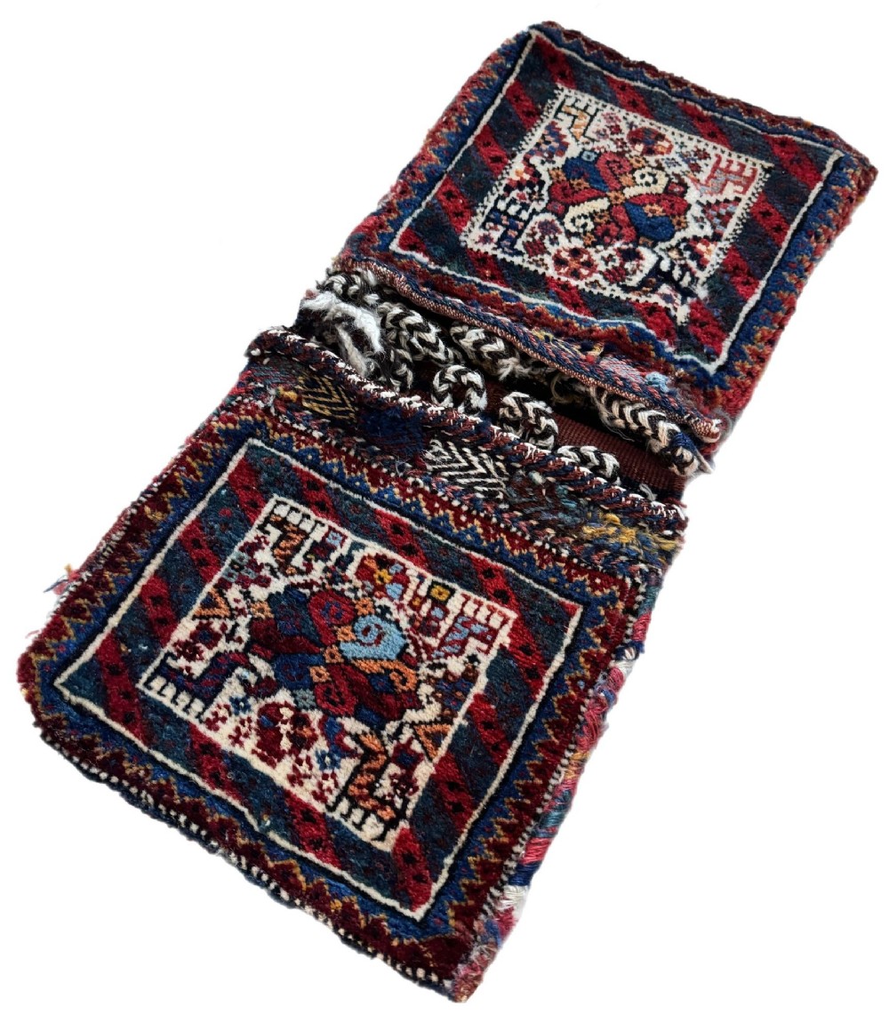 An antique handwoven Qashqai wool Khorjin double saddlebag featuring geometric medallions in red, navy, and cream with braided closure loops. View III