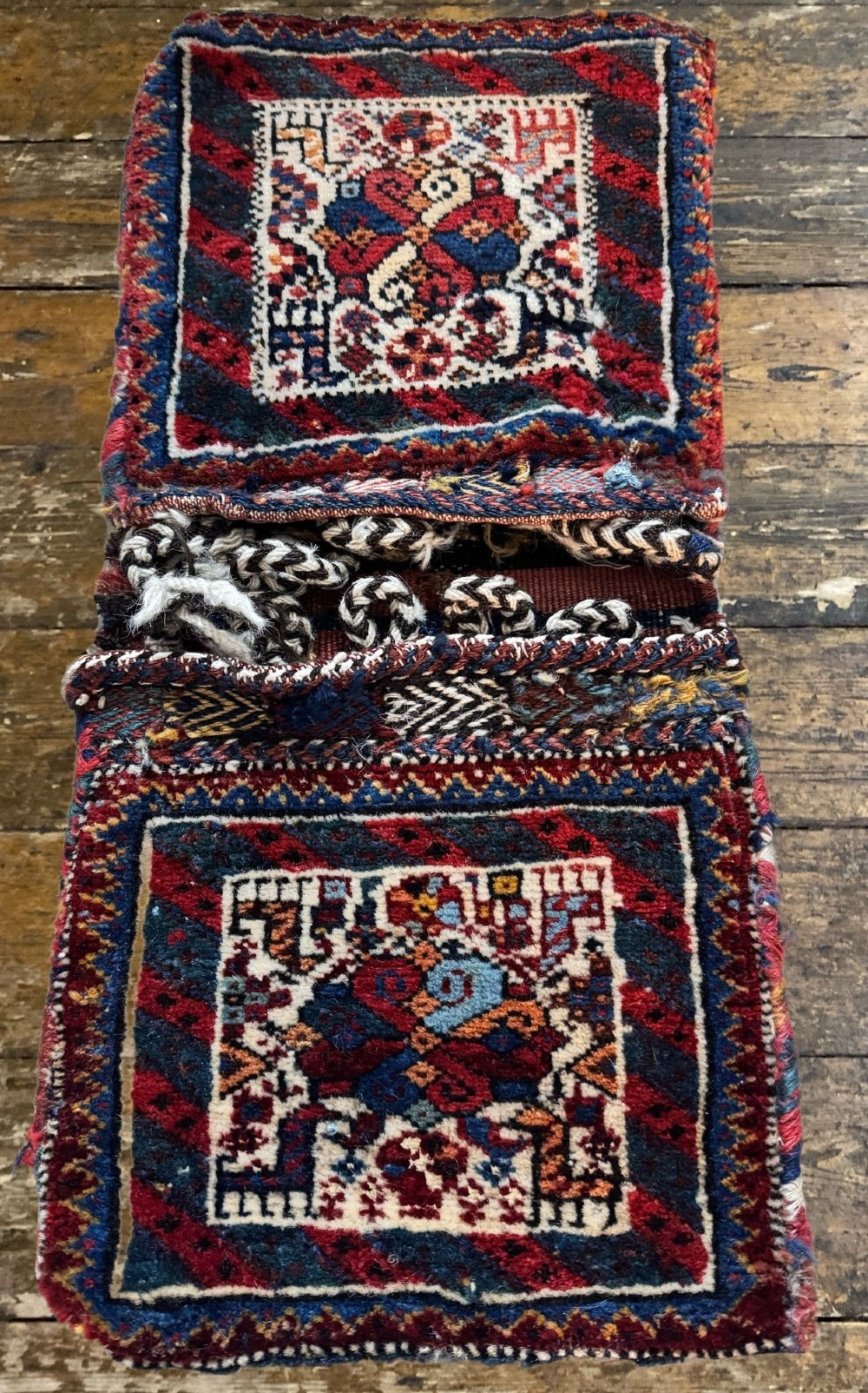 An antique handwoven Qashqai wool Khorjin double saddlebag featuring geometric medallions in red, navy, and cream with braided closure loops. View IV