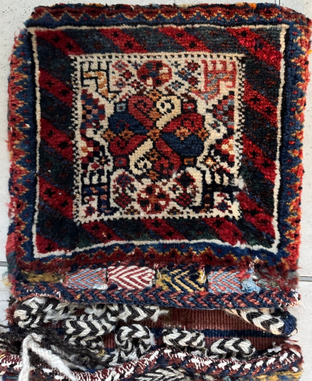 An antique handwoven Qashqai wool Khorjin double saddlebag featuring geometric medallions in red, navy, and cream with braided closure loops. View VIII