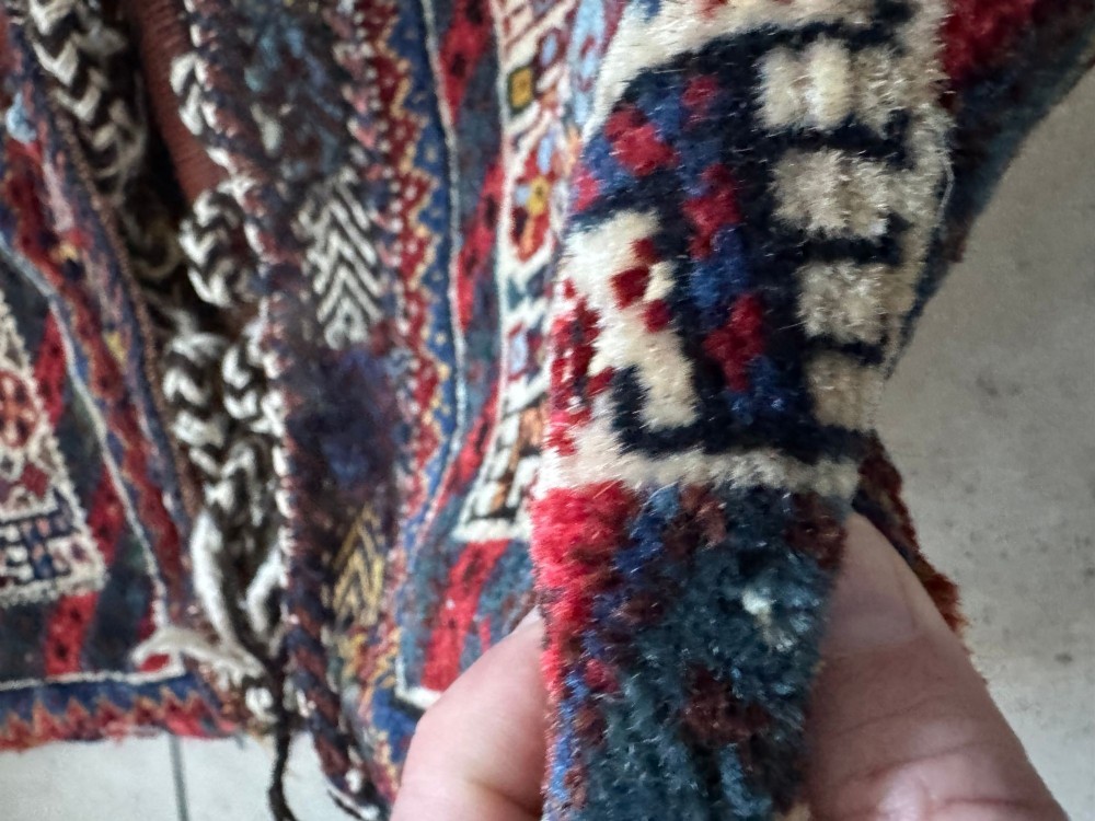 An antique handwoven Qashqai wool Khorjin double saddlebag featuring geometric medallions in red, navy, and cream with braided closure loops. View XV