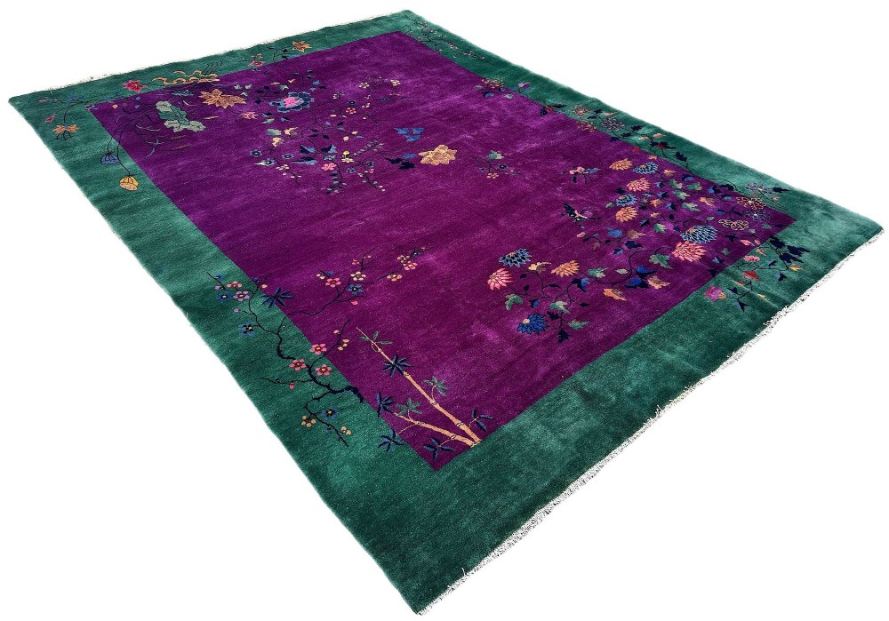 A large hand-knotted wool carpet featuring a vibrant magenta central field framed by a rich jade green border with asymmetrical floral and bamboo motifs. View III