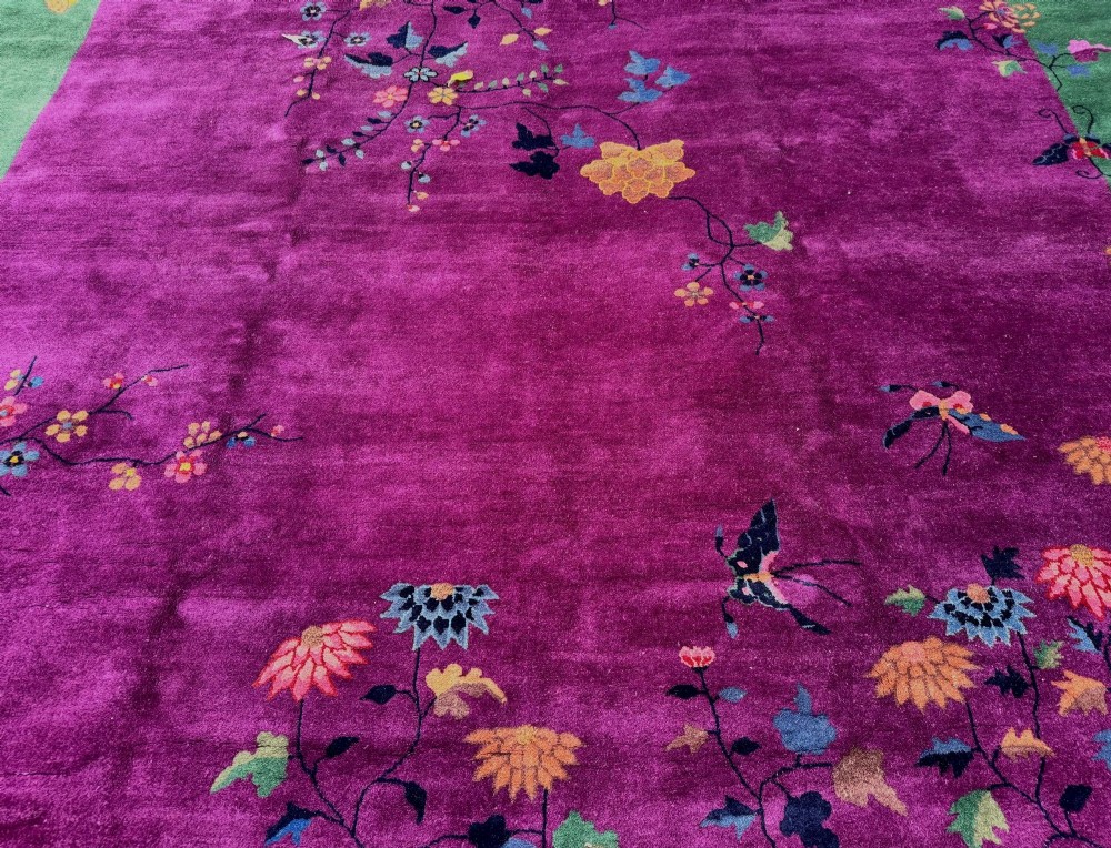 A large hand-knotted wool carpet featuring a vibrant magenta central field framed by a rich jade green border with asymmetrical floral and bamboo motifs. View IX