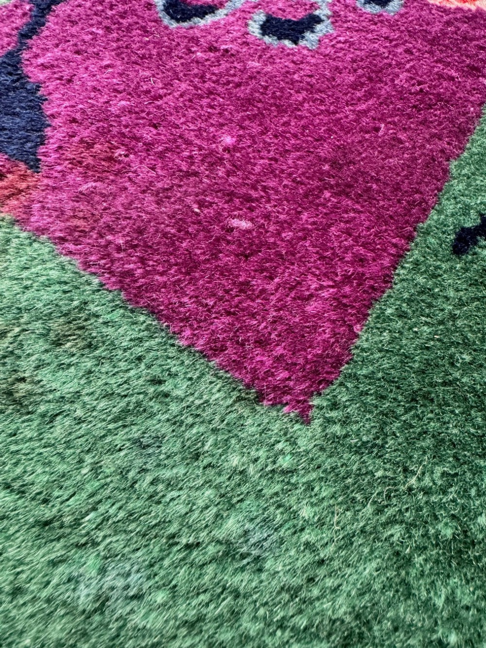A large hand-knotted wool carpet featuring a vibrant magenta central field framed by a rich jade green border with asymmetrical floral and bamboo motifs. View XI