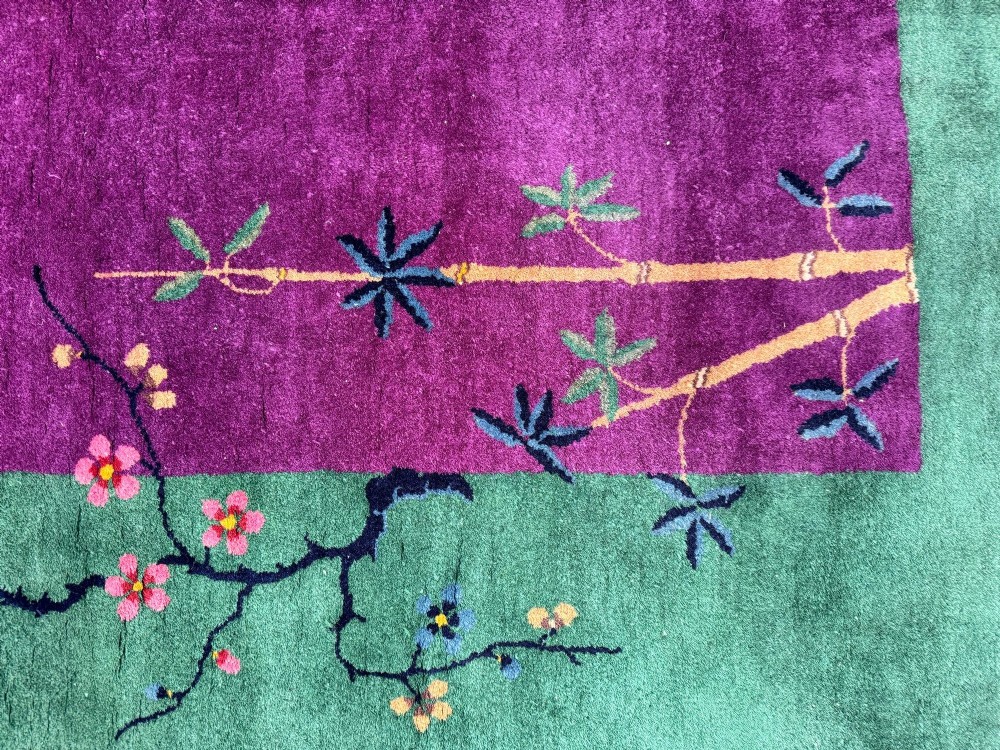 A large hand-knotted wool carpet featuring a vibrant magenta central field framed by a rich jade green border with asymmetrical floral and bamboo motifs. View XIV