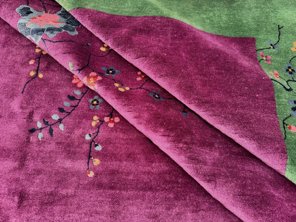 A large hand-knotted wool carpet featuring a vibrant magenta central field framed by a rich jade green border with asymmetrical floral and bamboo motifs. View XV
