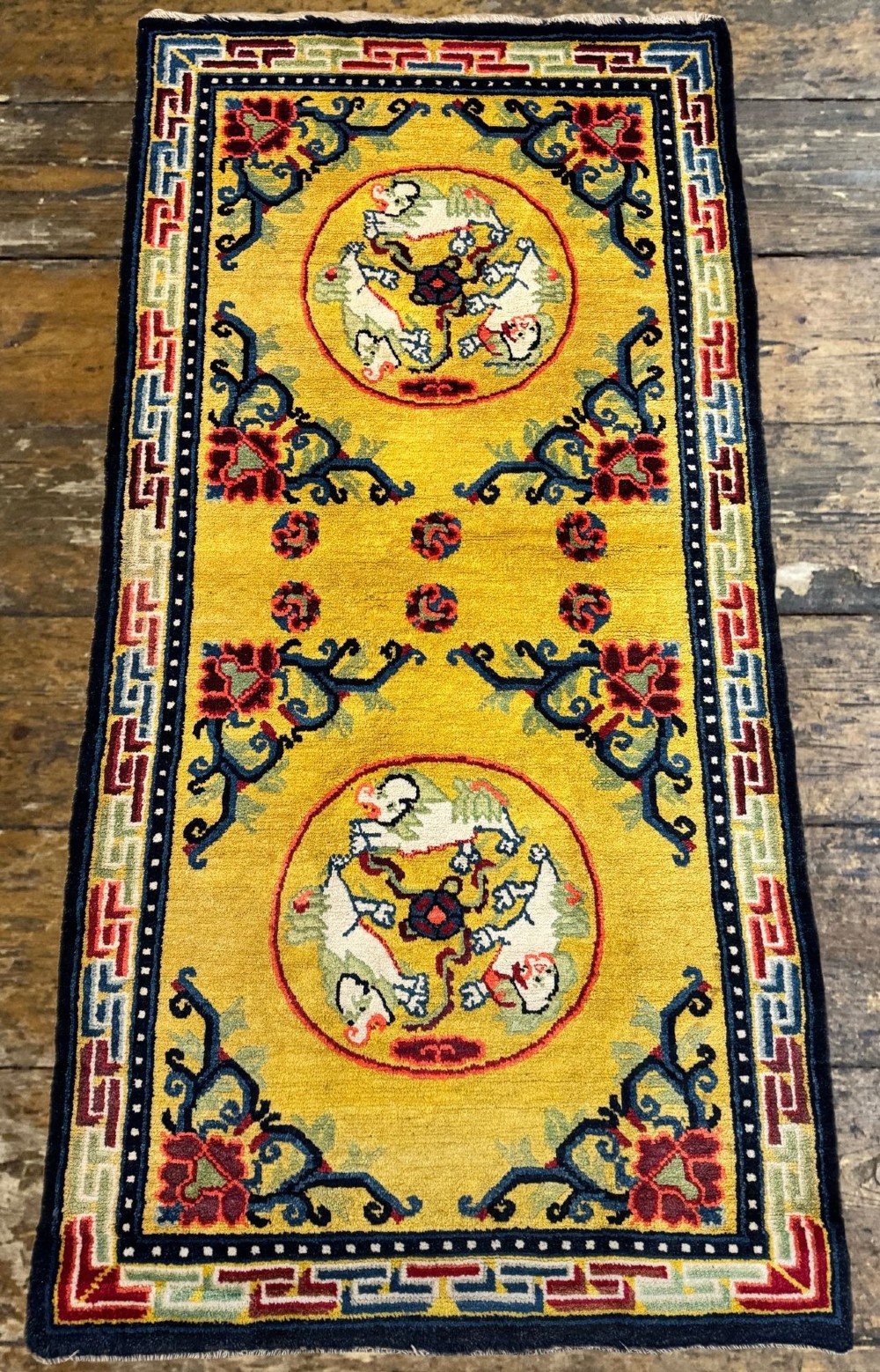 An antique hand-knotted Chinese Ningxia rectangular wool rug featuring a bright yellow field with two circular animal medallions, floral corner accents, and a blue geometric fretwork border. View IV