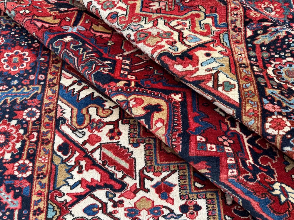 An antique hand-knotted Persian Heriz carpet featuring a prominent geometric central medallion on a rust red field with cream corner spandrels and a navy blue border. View XI