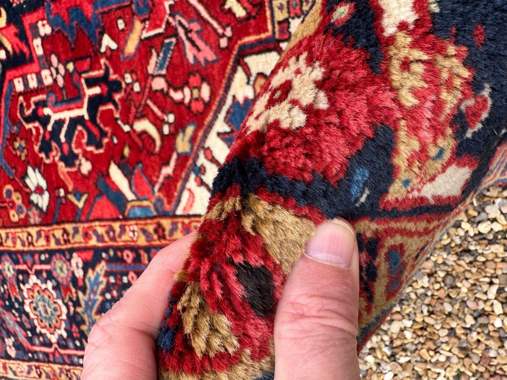 An antique hand-knotted Persian Heriz carpet featuring a prominent geometric central medallion on a rust red field with cream corner spandrels and a navy blue border. View XIII