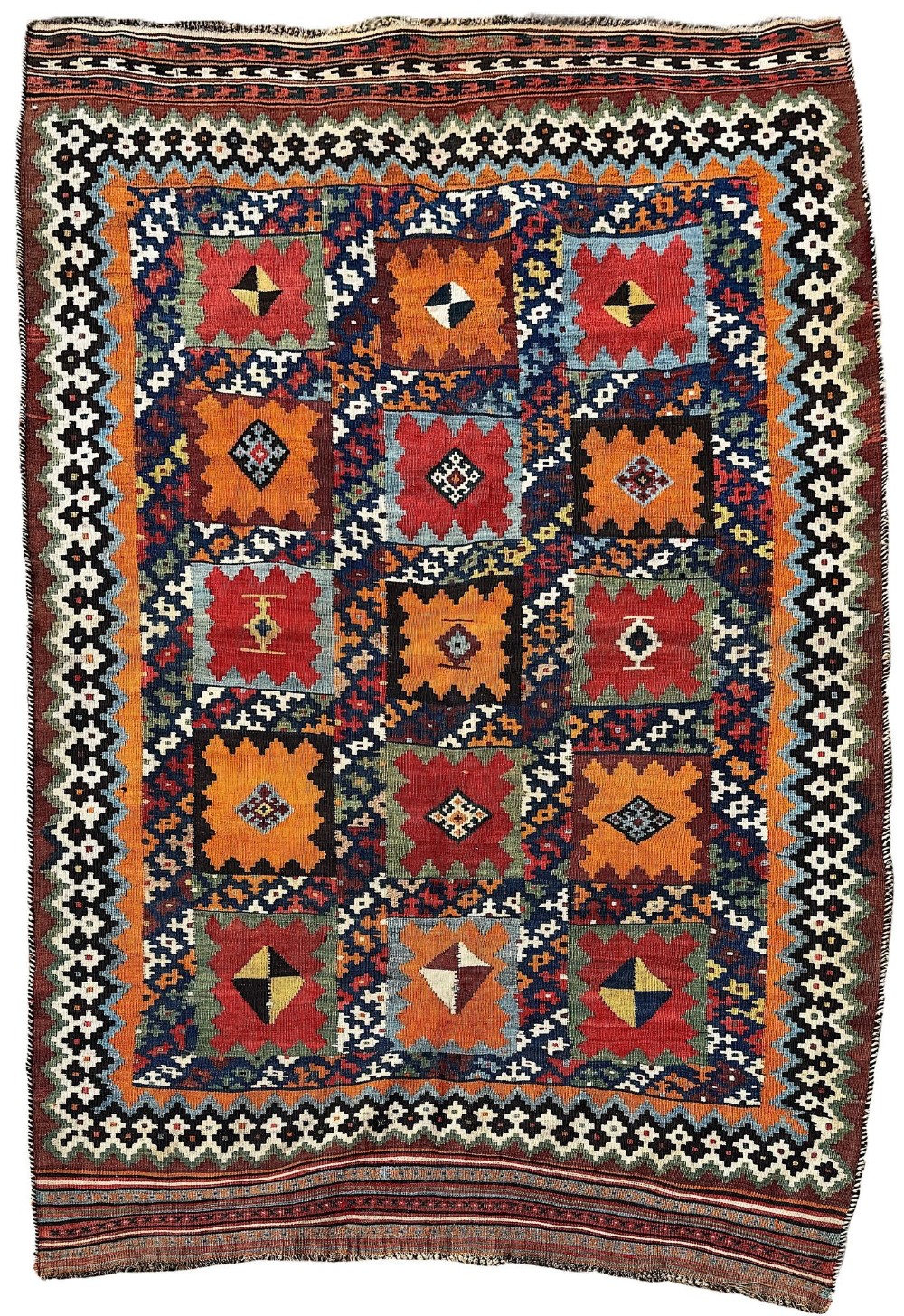 An antique handwoven Qashqai wool kilim rug featuring geometric stepped diamond motifs in terracotta red, ochre orange, indigo blue, and ivory.