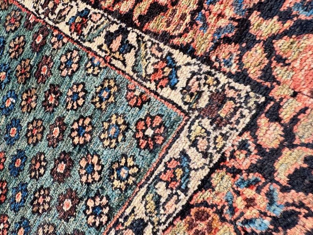 An antique hand-knotted Bakhtiar wool rug featuring a central terracotta stepped medallion on a dark indigo field filled with intricate floral motifs. View X